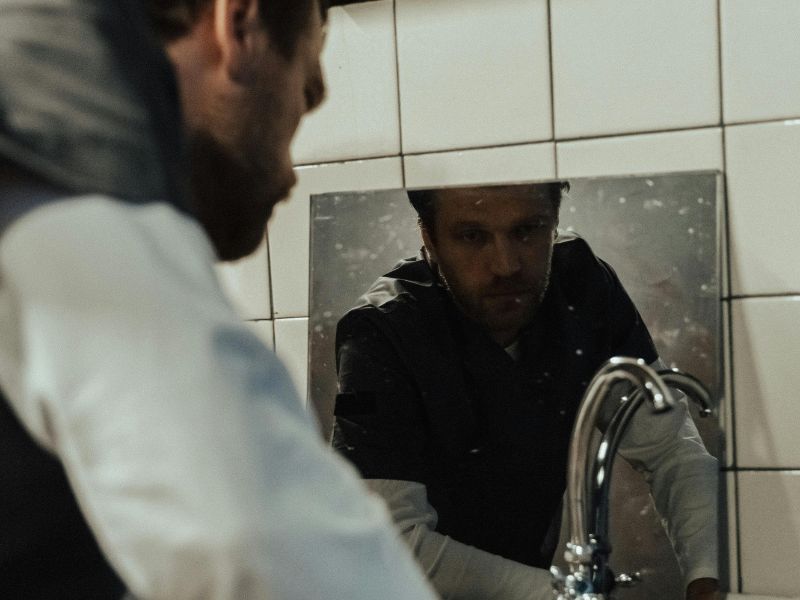 Man looking at himself in bathroom mirror during morning routine before work